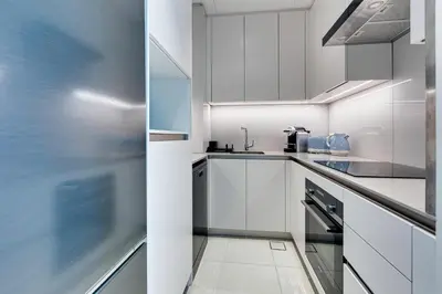 a white kitchen with white cabinets and appliances at Stylish 1BD apartment in Address Beach Residence in Dubai