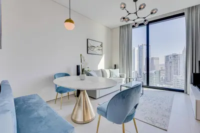a living room with a table and blue chairs at Stylish 1BD apartment in Address Beach Residence in Dubai