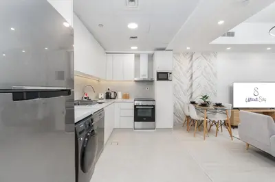 a kitchen with white cabinets and a table with chairs at Modern 1BR with City View Rooftop Pool Access in Dubai