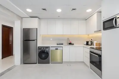 a kitchen with white cabinets and a washer and dryer at Modern 1BR with City View Rooftop Pool Access in Dubai