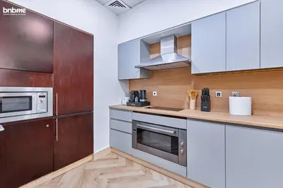 a kitchen with stainless steel appliances and wooden cabinets at bnbme - Beachfront 1BR Palm Jumeirah Apt w Balcony Sea Views Pool & Beach Access in Dubai
