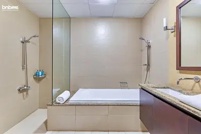 a bathroom with a tub and a shower and a sink at bnbme - Beachfront 1BR Palm Jumeirah Apt w Balcony Sea Views Pool & Beach Access in Dubai