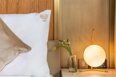 a bed with a white pillow and a lamp on a table at Voco Dubai Monaco, The Heart of Europe by IHG-Adult only in Dubai