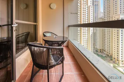 a balcony with a table and chairs looking out at the city at Spacious 3BR Apartment with Assistant Room in Sadaf 5 JBR by Deluxe Holiday Homes in Dubai