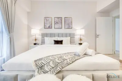 a white bedroom with a large bed and two lamps at Spacious 3BR Apartment with Assistant Room in Sadaf 5 JBR by Deluxe Holiday Homes in Dubai
