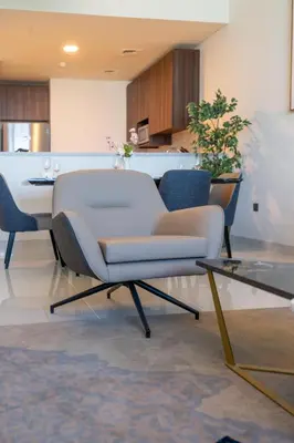 a living room with a white chair and a table at ON OFF HH-AVANI HOTEL-3BR -Full Palm View in Dubai