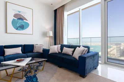 a living room with a blue couch and large windows at ON OFF HH-AVANI HOTEL-3BR -Full Palm View in Dubai