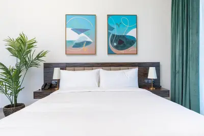 a bedroom with a white bed and three paintings on the wall at ON OFF HH-AVANI HOTEL-3BR -Full Palm View in Dubai