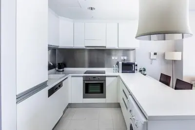 a white kitchen with white cabinets and appliances at Emaar Residences in Dubai