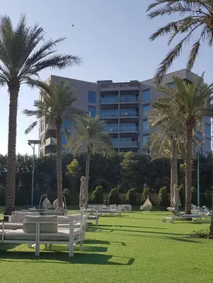 a park with benches and palm trees in front of a hotel at Elegant and comfortably furnished 2BRH apartment in a quiet area! in Dubai