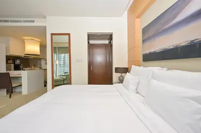 a large white bed in a room with a kitchen at Emaar Fashion Avenue - Formerly Address Dubai Mall Residence in Dubai