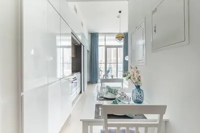 a white kitchen with a white table and a table and a table at Frank Porter - Studio One in Dubai