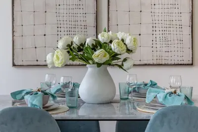 a white vase with white flowers on a table at Frank Porter - BLVD Heights T1 in Dubai