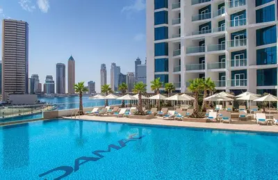 a swimming pool with chairs and umbrellas and a building at Damac Maison Prive Deluxe Studio with Water Canal View in Dubai