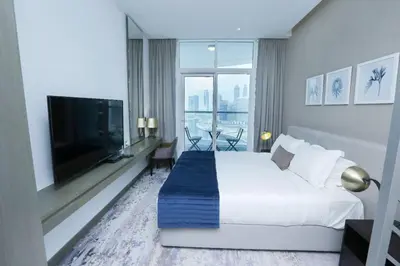 a hotel room with a bed and a flat screen tv at Damac Maison Prive Deluxe Studio with Water Canal View in Dubai