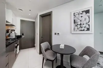 a kitchen with a table and chairs in a room at Damac Maison Prive Deluxe Studio with Water Canal View in Dubai