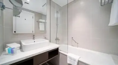 a white bathroom with a sink and a mirror at Damac Maison Prive Deluxe Studio with Water Canal View in Dubai