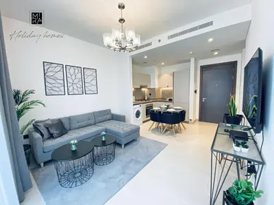 a living room with a couch and tables and a kitchen at Mira Holiday Homes - Newly Furnished 1 bedroom in Creek Vista Tower B Sobha Hartland in Dubai