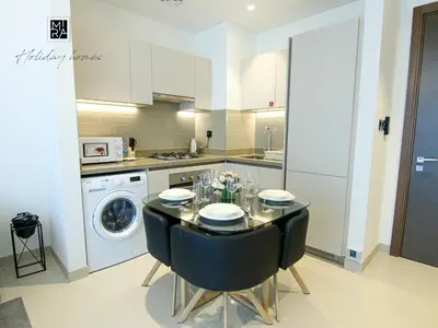 a kitchen with a dining room table and a dishwasher at Mira Holiday Homes - Newly Furnished 1 bedroom in Creek Vista Tower B Sobha Hartland in Dubai