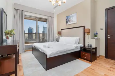 a bedroom with a bed and a desk and a window at White Sage - Elite Residence 1 bedroom in Dubai