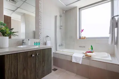 a bathroom with a sink and a tub and a shower at Frank Porter - Executive Tower F in Dubai
