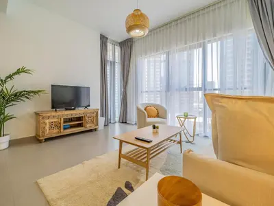 a living room with a couch and a tv at Charming Tropical Apartment Minutes To Dubai Mall in Dubai