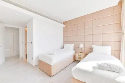 two beds in a room with white walls at Premium 2+1 BR condo in the heart of Bluewaters Island in Dubai