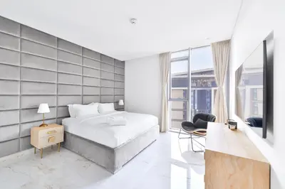 a white bedroom with a bed and a chair at Premium 2+1 BR condo in the heart of Bluewaters Island in Dubai