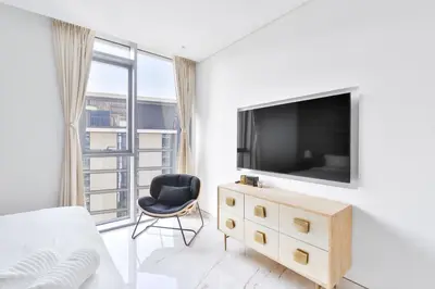 a white bedroom with a television and a chair at Premium 2+1 BR condo in the heart of Bluewaters Island in Dubai