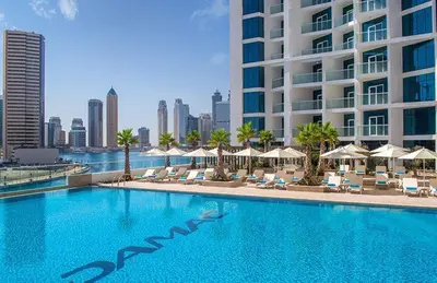 a large swimming pool with chairs and umbrellas and a building at DAMAC MAISON PRIVE in Dubai