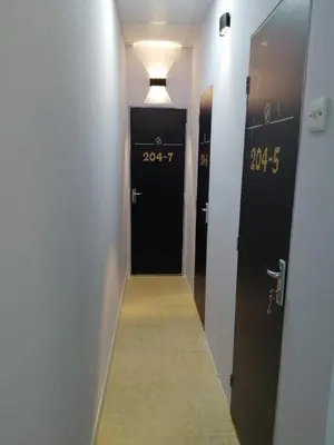 a hallway with two black doors and a long aisle at AlBarsha 1 Hostel by PHM in Dubai