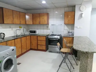 a kitchen with wooden cabinets and a dishwasher at AlBarsha 1 Hostel by PHM in Dubai