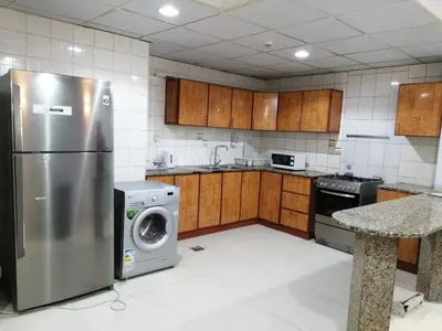 a kitchen with a refrigerator and a washing machine at AlBarsha 1 Hostel by PHM in Dubai