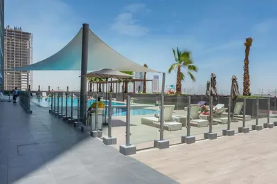 a pool with chairs and umbrellas next to a building at Bloom Height Tower in Dubai