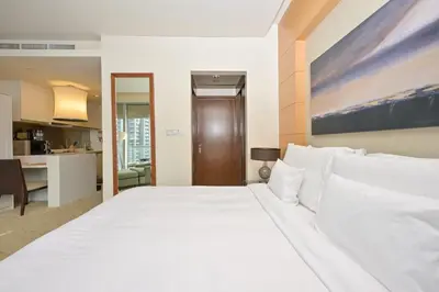 a large white bed in a room with a kitchen at FAHH - Spacious Studio in Emaar Fashion Avenue in Dubai