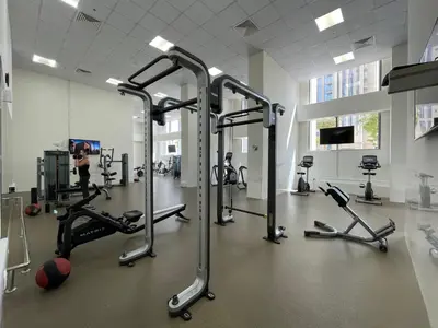 a gym with several tread machines and a woman in the background at The Smart Concierge - Amna Tower in Dubai