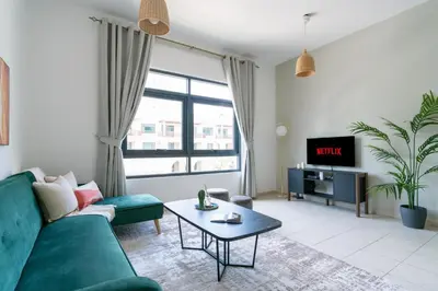 a living room with a green couch and a tv at GuestReady Holiday Homes - The Green Scape in Dubai