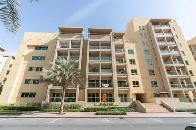 an apartment building with a palm tree in front of it at GuestReady Holiday Homes - The Green Scape in Dubai
