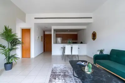 a living room with a green couch and a kitchen at GuestReady Holiday Homes - The Green Scape in Dubai