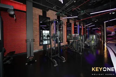 a gym with rows of exercise equipment on the floor at Modern & Stylish Studio in JVT in Dubai