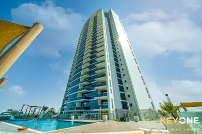 a tall building with a swimming pool in front of it at Modern & Stylish Studio in JVT in Dubai