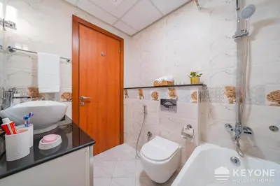 a white bathroom with a toilet and a sink at Modern & Stylish Studio in JVT in Dubai