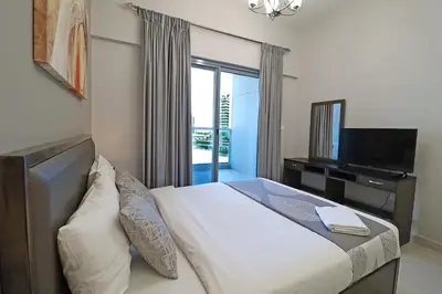 a bedroom with a bed with a television and a window at Spacious Apartment with Balcony Near Dubai Mall in Dubai