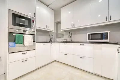a white kitchen with white cabinets and a microwave at The Marina PENTHOUSE near JBR 46th Floor in Dubai