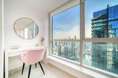 a pink chair in a white room with a large window at The Marina PENTHOUSE near JBR 46th Floor in Dubai