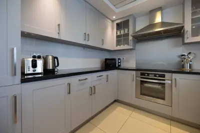 a white kitchen with white cabinets and appliances at Signature 2BR with Burj Khalifa & Fountain View in Dubai