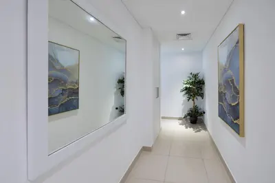 a hallway with white walls and paintings on the walls at Signature 2BR with Burj Khalifa & Fountain View in Dubai