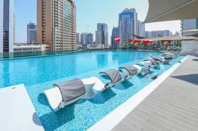 a large swimming pool with lounge chairs on a building at Luxury MAG 318 Studio Near Dubai Mall in Dubai