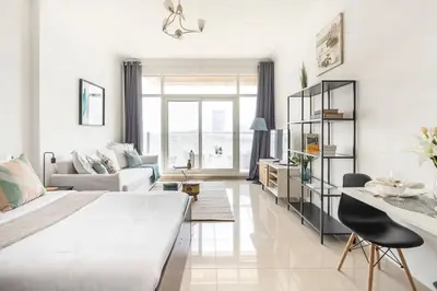 a white bedroom with a large bed and a living room at Frank Porter - Siraj Tower in Dubai