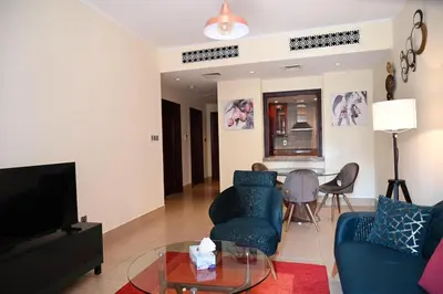 a living room with a blue couch and a tv at Burj Khalifa view, birds chirping, cozy and stylish in Dubai